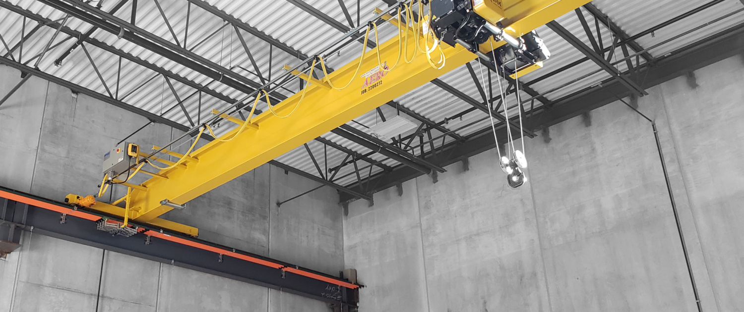 interior of a ware house with multiple yellow ceiling crane beams - Aero Material Handling Inc