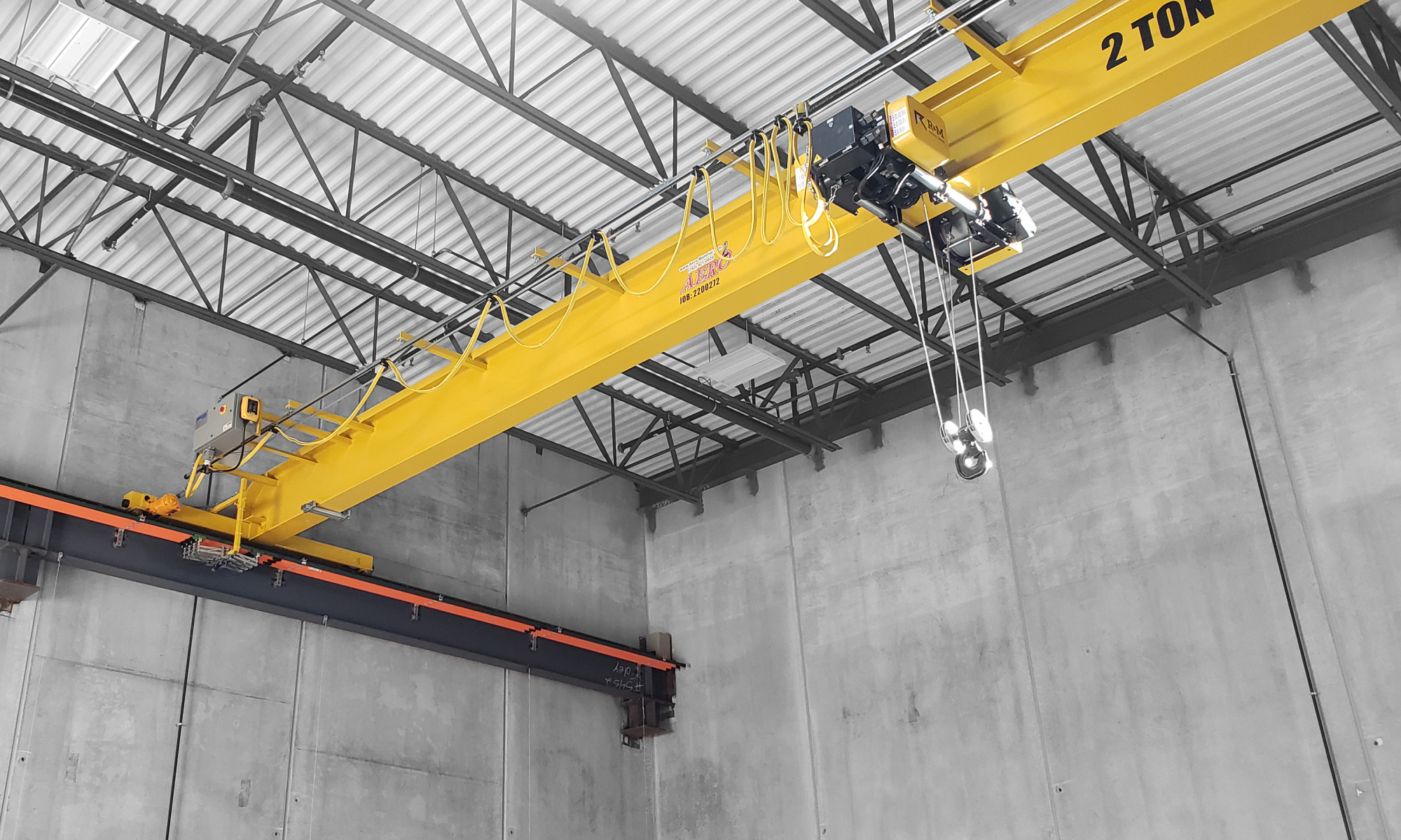 interior of a ware house with multiple yellow ceiling crane beams - Aero Material Handling Inc