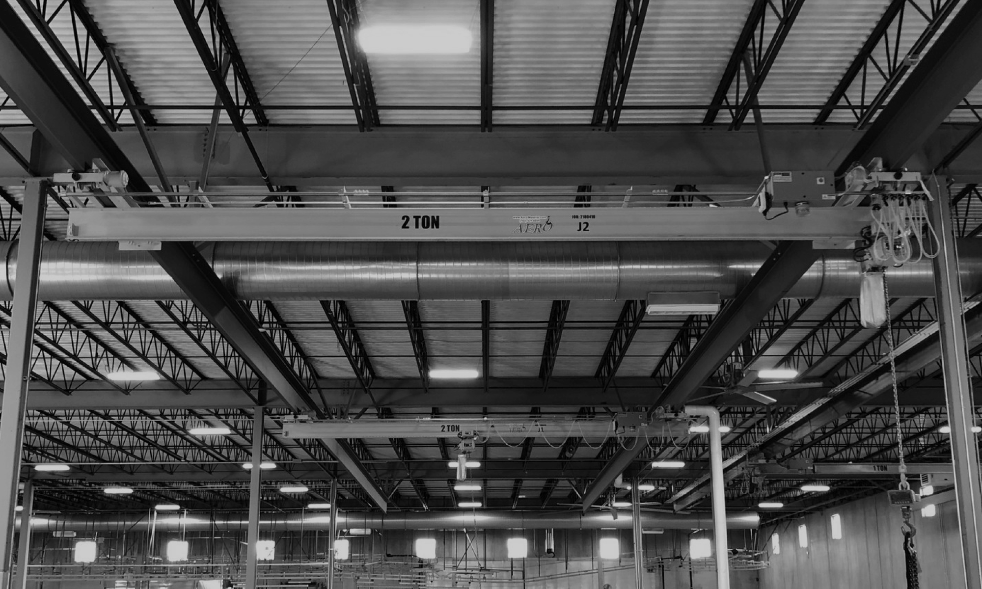 interior of a ware house with multiple yellow ceiling crane beams - Aero Material Handling Inc