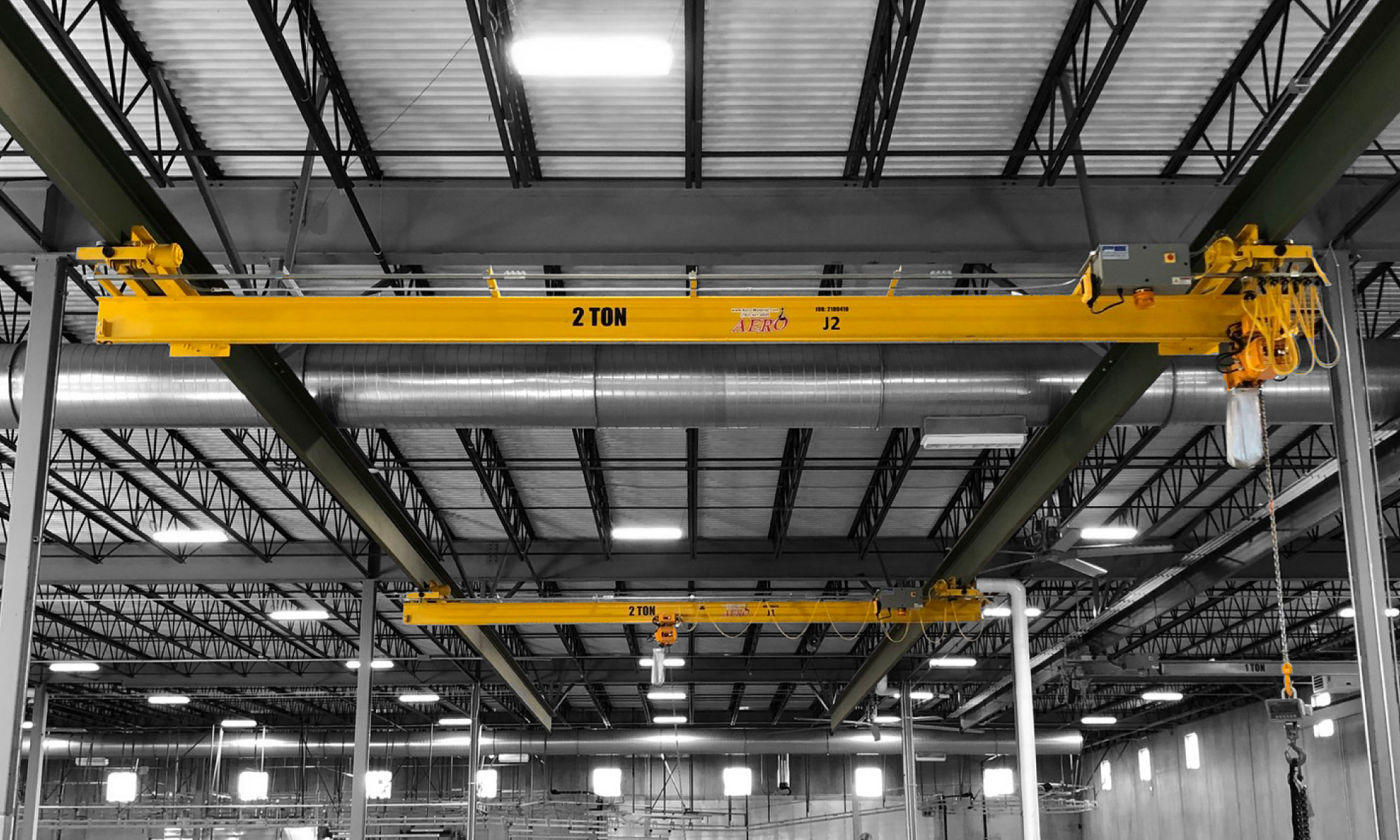 interior of a ware house with multiple yellow ceiling crane beams - Aero Material Handling Inc